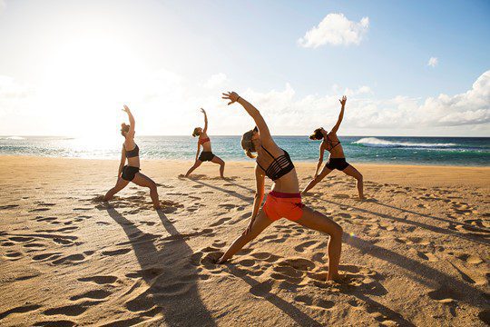 group yoga stretch on beach